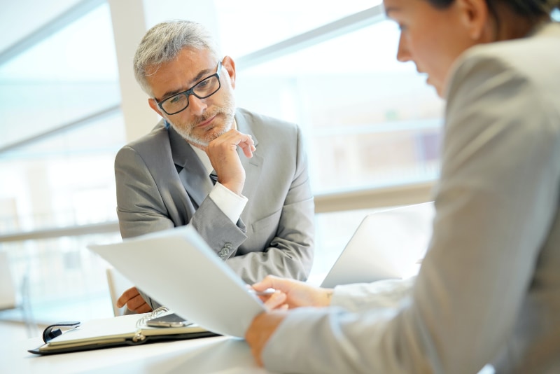 older male businessman looking over papers in meeting