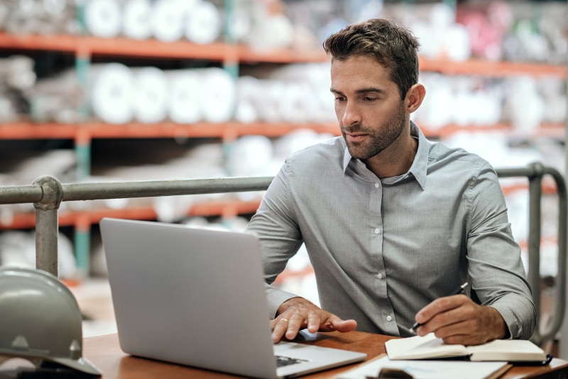 worker in warehouse sitting at a desk with a laptop computer